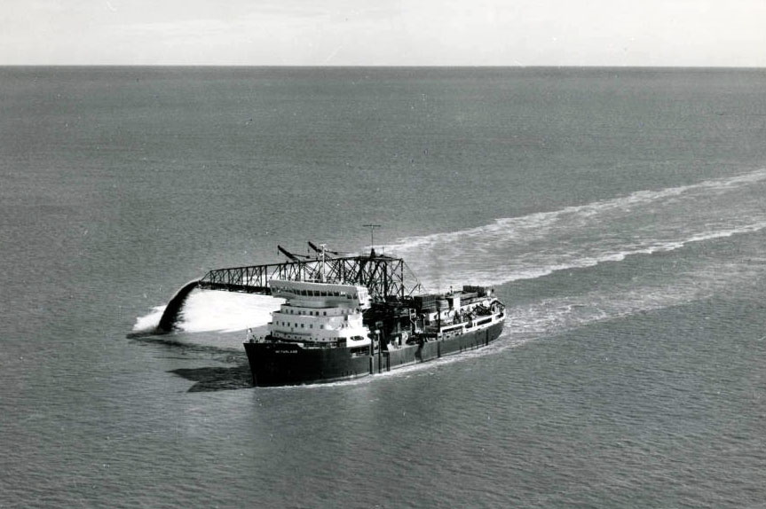 A large dredge boat discharging earth from its spout